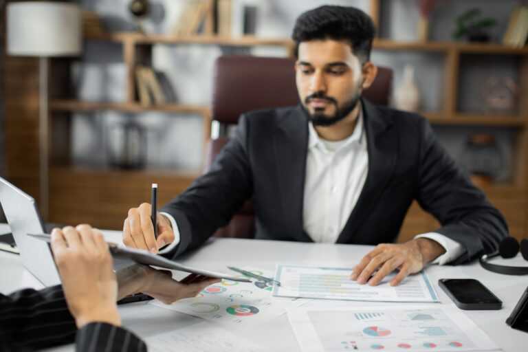 Focused young businessman signing agreement with skilled female lawyer.